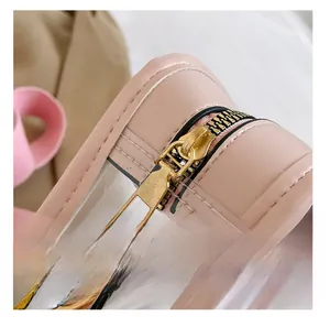 Detail of pink translucent bag showing smooth gold metal zipper and leather trim