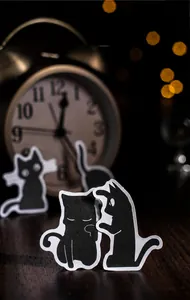 Macro shot of black cat stickers with white outlines on a warm bokeh background