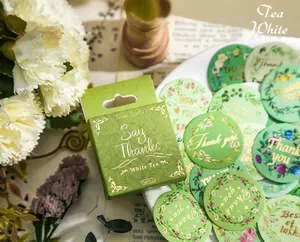 Gros plan d'autocollants de couronnes botaniques dans un coffret cadeau vert White Tea de 50