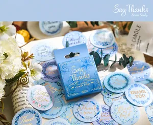 Détail de 50 autocollants floraux bleus avec script de remerciement sur pages vintage