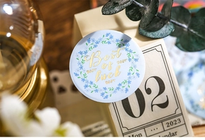 Detail of floral wreath sticker badge featuring gold foil Best of luck text for journaling