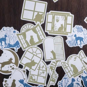 Vintage cat silhouette decorative stickers with gold-green and deep blue accents on dark wood