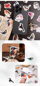 Close-up of bird-themed scrapbooking stickers applied to a phone and vintage book