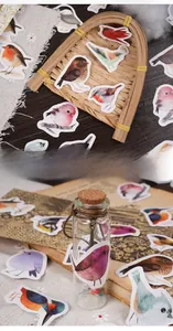 Detailed view of colorful bird stickers used for decorating vintage journals and glass bottles