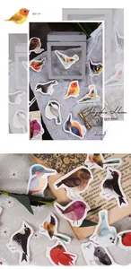 Detailed view of watercolor bird stickers on vintage books and floral fabric