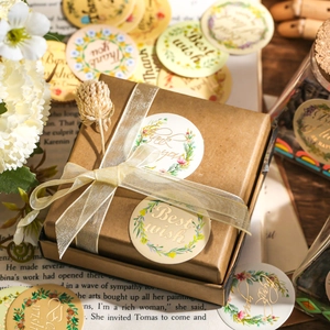 Botanical wreath stickers with gold lettering on kraft paper gift box with dry flowers
