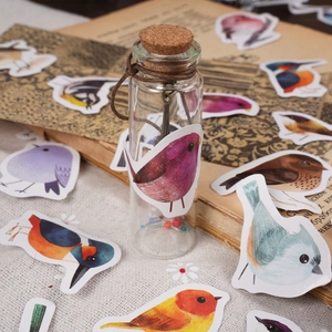 Artistic bird stickers with a vintage glass bottle and retro decor on white linen fabric