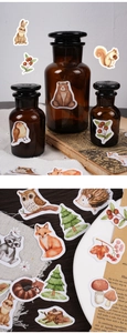 Close-up of watercolor forest animal stickers on vintage paper and a medicine bottle