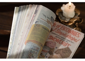 Close-up of vintage scrapbook paper featuring retro advertisements on a dark wooden desk
