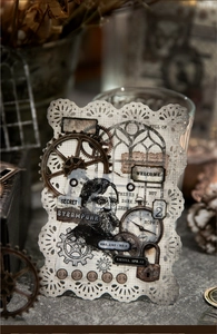 Detail of steampunk decorative card with vintage clockwork and gear motifs on lace paper