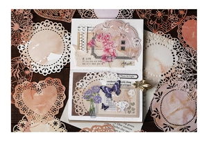 Close-up of vintage lace doilies and floral butterfly stickers for DIY scrapbooking