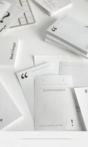 Minimalist notepad cards with black punctuation symbols and English life tips on a desk