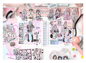 Detail of cute anime girl stickers on a pink desk setup for DIY journaling