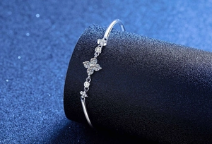 Macro shot of polished silver bangle featuring a sparkling gemstone four-leaf clover detail