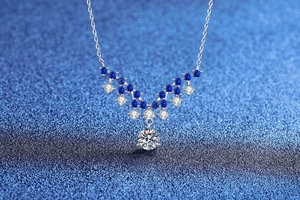 Macro shot of V-shaped sterling silver necklace with blue stones on a starry background