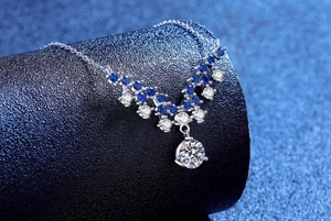 Detailed view of S925 silver V-shaped necklace with blue gems and a large round moissanite