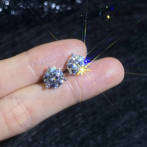 Classic round cut moissanite earrings with 3-prong silver setting held between fingers