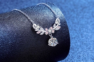 Detailed close-up of 1ct moissanite necklace with leaf design on a blue pedestal