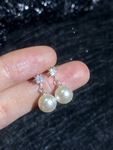 Macro detail of S925 sterling silver star earrings with white pearls held by hand