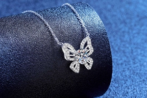 Macro detail of silver butterfly pendant with 1 carat moissanite on blue display