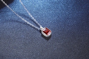 Macro di un ciondolo rettangolare con rubino su catenina minimalista in argento S925