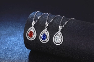 Macro view of teardrop sapphire, ruby, and moissanite pendants on silver chains