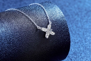 Gros plan du collier pendentif X en argent S925 avec moissanite brillante sur support bleu