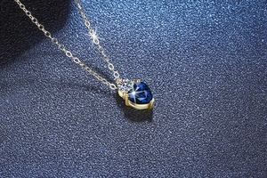 Makroaufnahme eines herzförmigen blauen Saphiranhängers an einer Goldkette mit Diamant