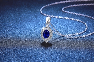 Macro di un ciondolo in argento S925 con zaffiro blu ovale e alone di pietre bianche lucide