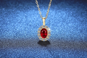 Detalle de un colgante de rubí ovalado con halo de diamantes en cadena de oro