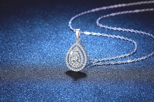 Macro detail of pear-shaped teardrop pendant necklace with double halo diamond setting