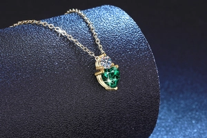 Detailaufnahme der Goldkette mit herzförmigem Smaragdstein und rundem Kristallbesatz