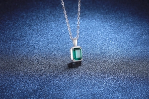 Detailopname van een rechthoekige smaragdgroene hanger aan een S925 zilveren ketting