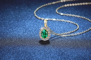 Detalle del collar de esmeralda con engaste de oro y diamantes brillantes en fondo azul