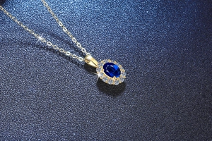 Vista macro de collar de oro con colgante de zafiro azul ovalado y halo de diamantes