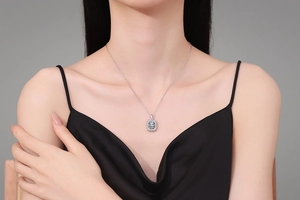 Close-up of a square-cut moissanite pendant necklace worn by a model on a black dress
