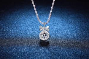 Macro shot of 1 carat moissanite halo pendant with diamond-encrusted bow on silver chain