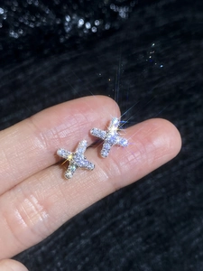 Detailed macro view of S925 sterling silver X-shaped earrings with shimmering moissanite