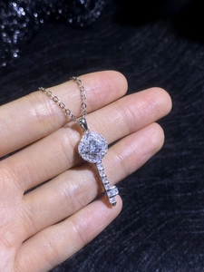 Close-up of S925 sterling silver key necklace with moissanite pavé on black fabric