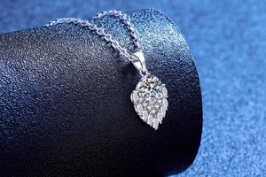 Macro side view of sparkling S925 silver moissanite water drop pendant on blue background