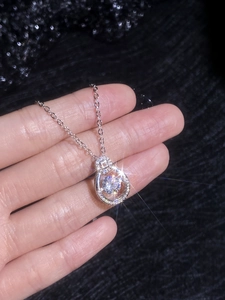 Macro shot of silver teardrop pendant featuring a dancing moissanite stone on an O-chain