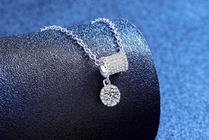 Macro shot of silver moissanite cylinder pendant with halo-set stone on fine chain