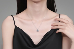 Detailed view of an elegant S925 sterling silver moissanite pendant on a black silk dress