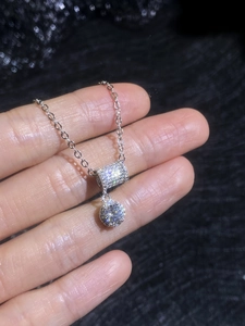 Macro detail of silver cylinder pendant necklace with sparkling pave moissanite stones