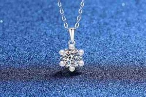 Macro shot of S925 silver snowflake pendant with moissanite and pearls on blue background