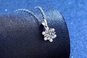 Macro detail of snowflake pendant with moissanite and pearls on elegant blue background