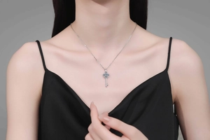 Detailed close-up of a silver sunflower key pendant necklace worn on a black silk dress
