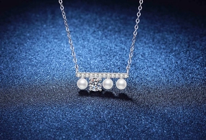 Macro d'un collier en argent S925 avec trois perles blanches et des pierres de moissanite