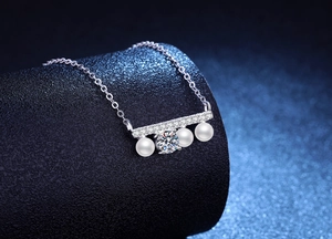 Détail macro du collier de perles en argent avec barre horizontale et pierre centrale brillante