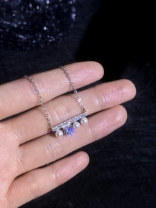 Détail du pendentif barre en argent avec pierres étincelantes et quatre perles blanches